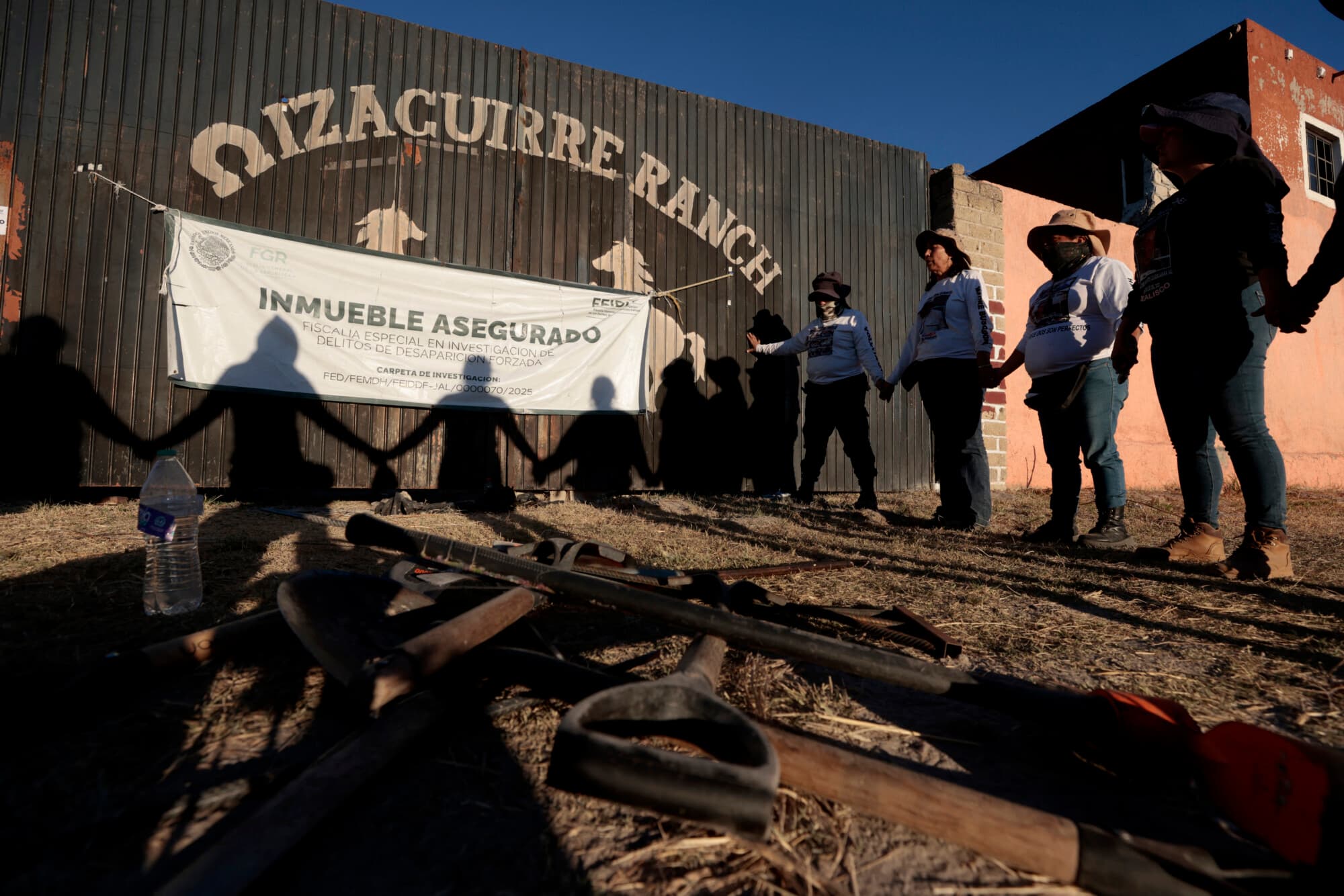Miembros del colectivo "Guerreros Buscadores de Jalisco" rezan a la entrada del Rancho Izaguirre tras una búsqueda sobre el terreno de sus familiares desaparecidos en los alrededores, días antes del primer aniversario de su descubrimiento, en Teuchitlán, Jalisco, México, el 18 de febrero de 2026. El 5 de marzo de 2025, el colectivo "Guerreros Buscadores de Jalisco" realizó una redada en el Rancho Izaguirre, donde encontraron cientos de indicios que apuntaban a que el lugar había sido utilizado como centro de reclutamiento para el crimen organizado. (AFP vía Getty Images)