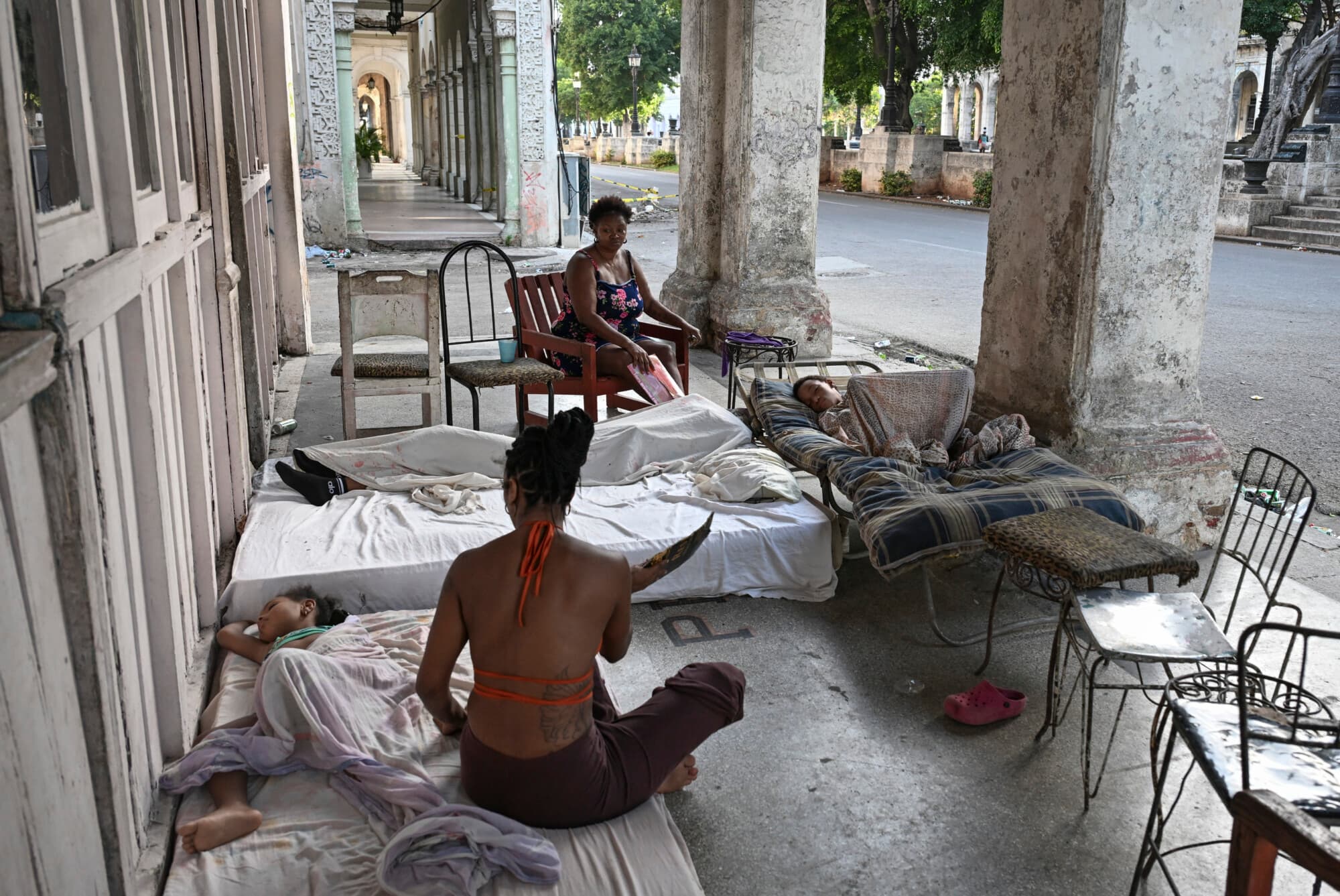 Una familia descansa sobre colchones en la entrada de un edificio en la avenida del Prado durante un apagón en La Habana el 7 de julio de 2026. (YAMIL LAGE / AFP vía Getty Images)