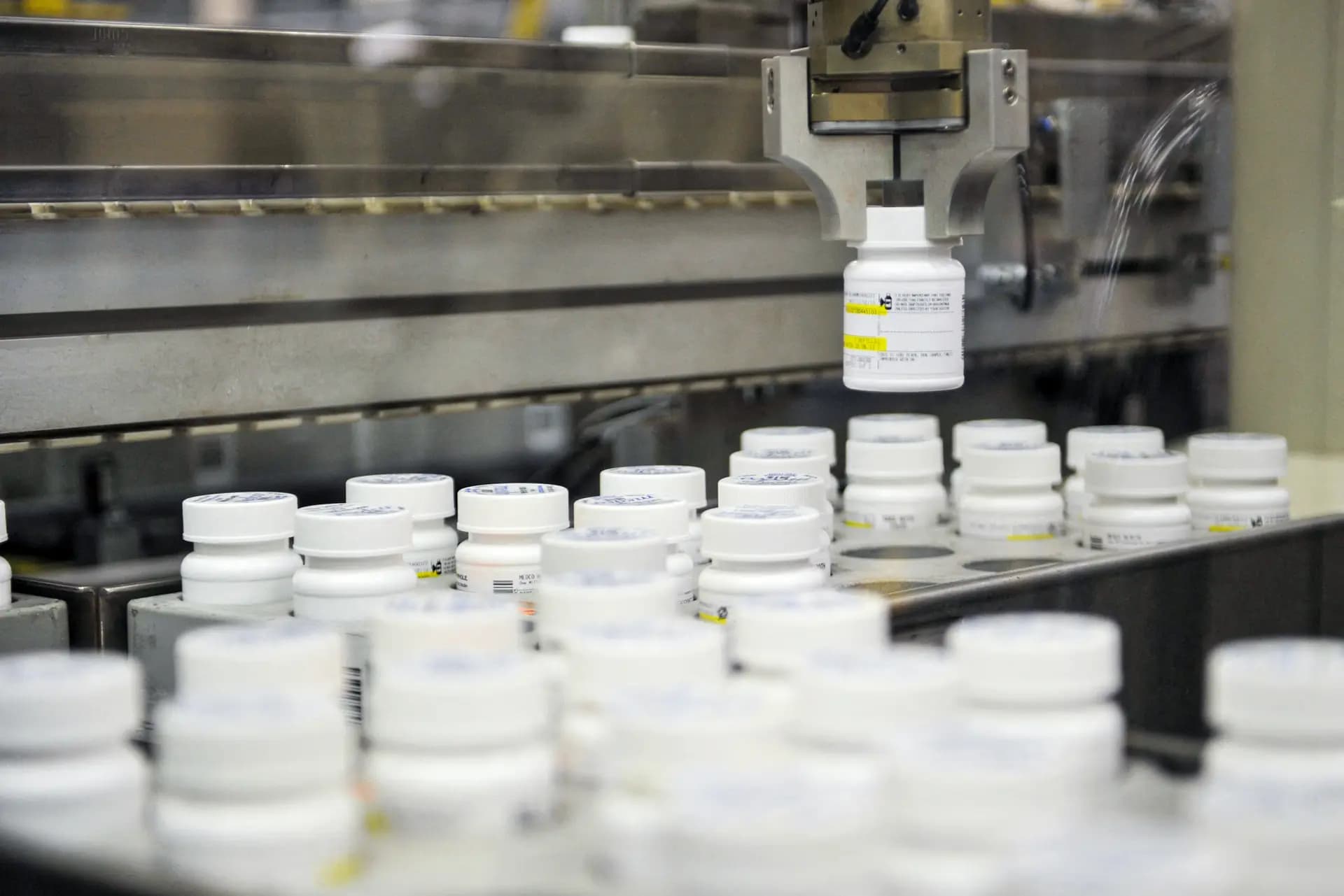 <em>Un brazo robótico recoge un frasco de pastillas recetadas en la planta de la farmacia Medco en Willingboro, Nueva Jersey, el 2 de diciembre de 2010. Hoy en día, cada pastilla recetada pasa por todas las manos, desde la fábrica hasta el mostrador de la farmacia, probablemente pertenece a la misma gran corporación de atención médica. (Stan Honda / AFP vía Getty Images)</em>