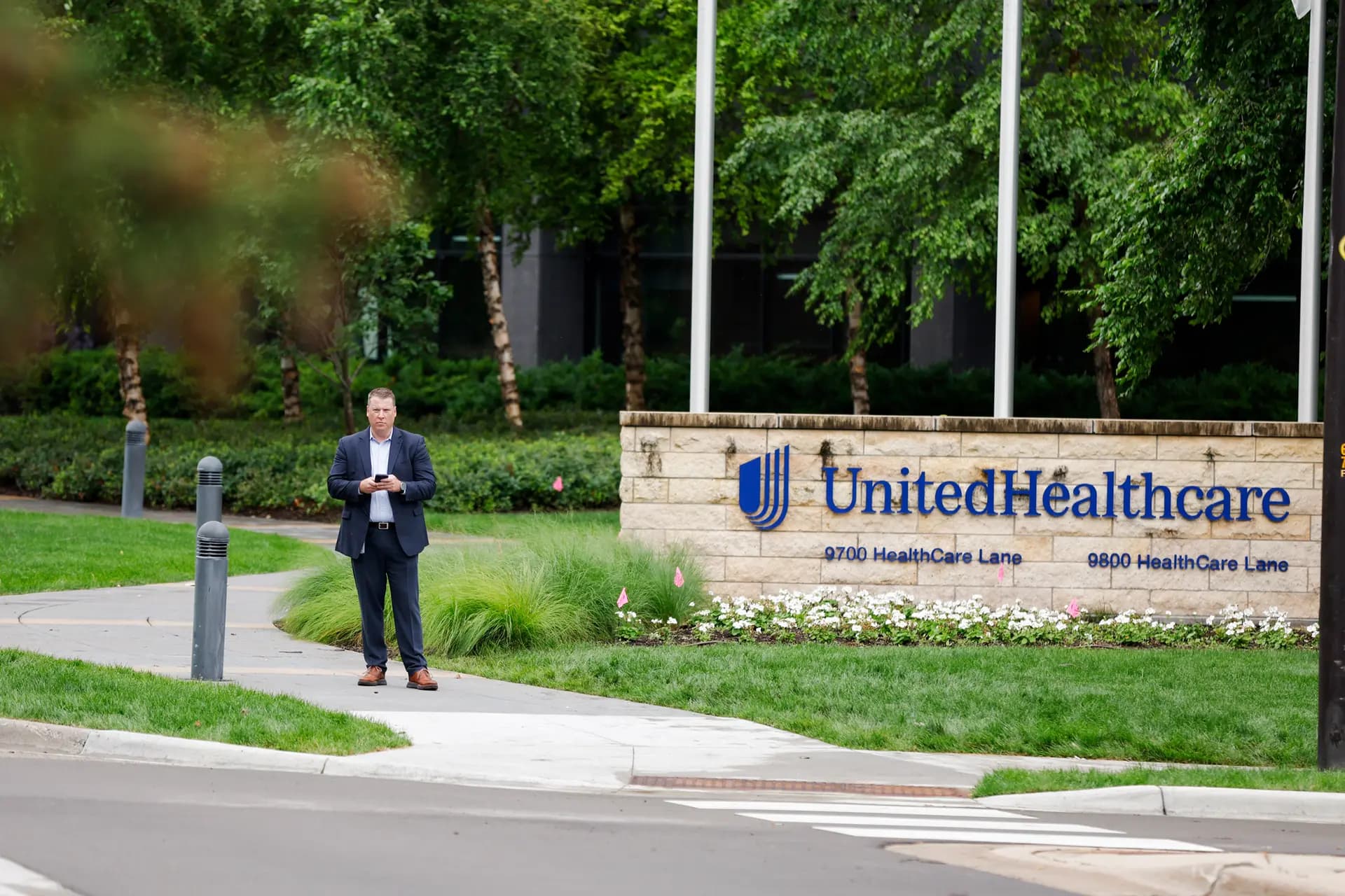 <em>Un hombre se encuentra de pie frente al campus de United Healthcare en Minnetonka, Minnesota, el 15 de julio de 2024. La compañía comenzó en la década de 1970 como un pequeño grupo de organizaciones de mantenimiento de la salud, y luego creció mediante la adquisición de compañías de seguros y proveedores de atención médica como consultorios médicos y farmacias. (David Berding/Getty Images para People's Action Institute).</em>