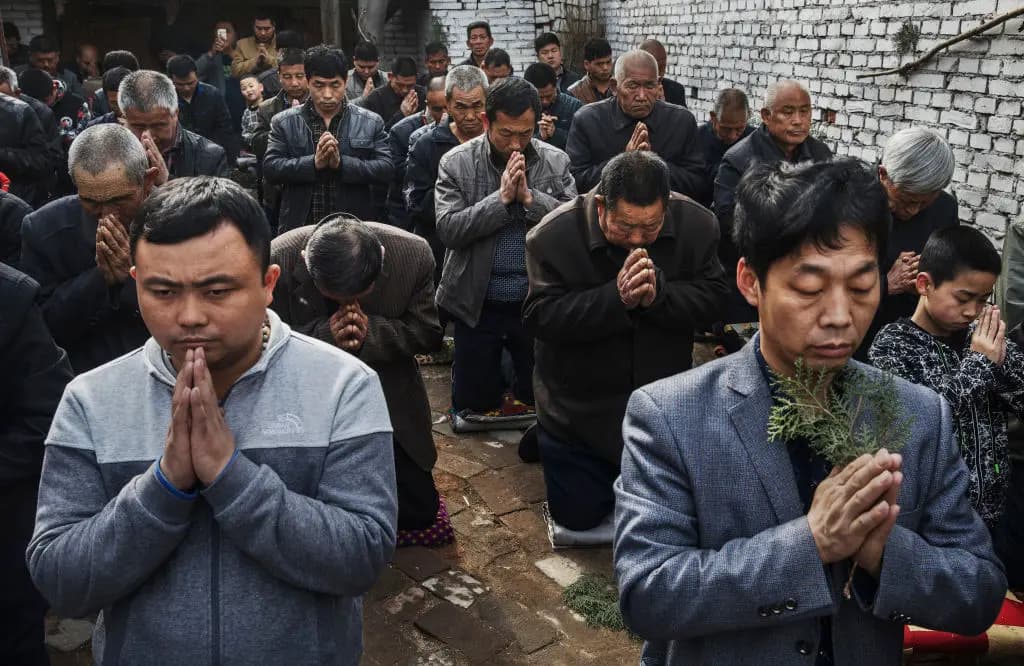 Fieles católicos chinos se arrodillan y rezan durante la misa del Domingo de Ramos, en la Semana Santa, en una iglesia "clandestina" o "no oficial" cerca de Shijiazhuang, en la provincia de Hebei, el 9 de abril de 2017. (Kevin Frayer/Getty Images)<br/>