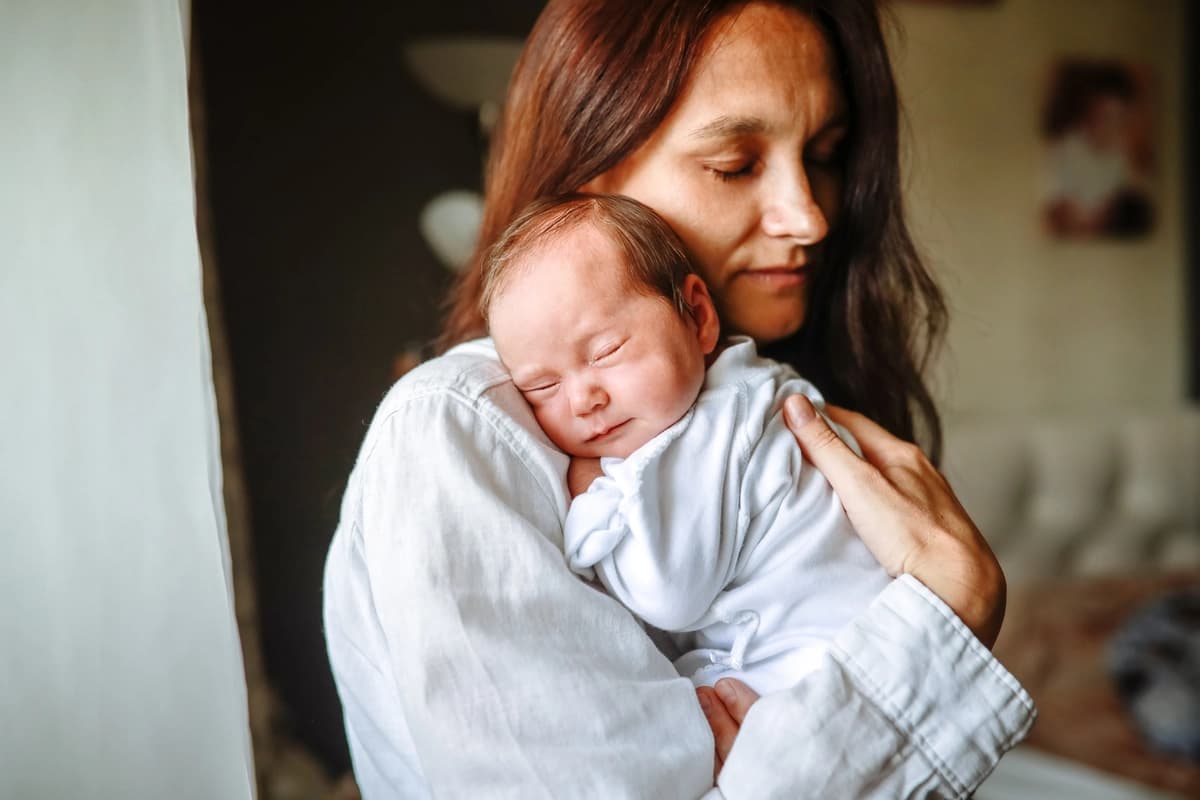 Una madre mece a su hija recién nacida sobre su hombro en casa. (Natalia Lebedinskaia/Getty Images)