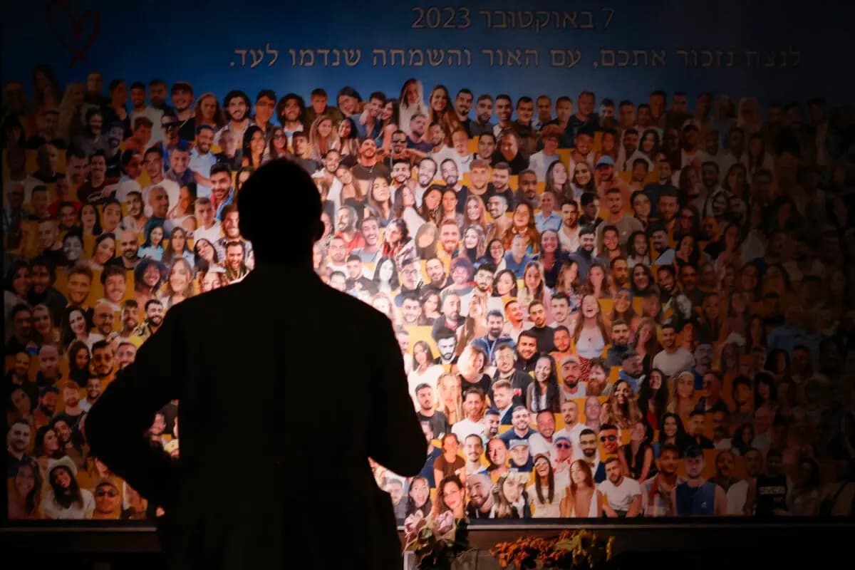 <em>Una persona observa un collage mientras familiares y simpatizantes de los rehenes israelíes, secuestrados durante el ataque de Hamás del 7 de octubre de 2023, asisten al monumento conmemorativo Nova cerca del lugar donde se celebraba el festival de música Nova, atacado por terroristas, durante el primer aniversario de los ataques, en el kibutz Reim, Israel, el 7 de octubre de 2024. (John Wessels/AFP vía Getty Images).</em>