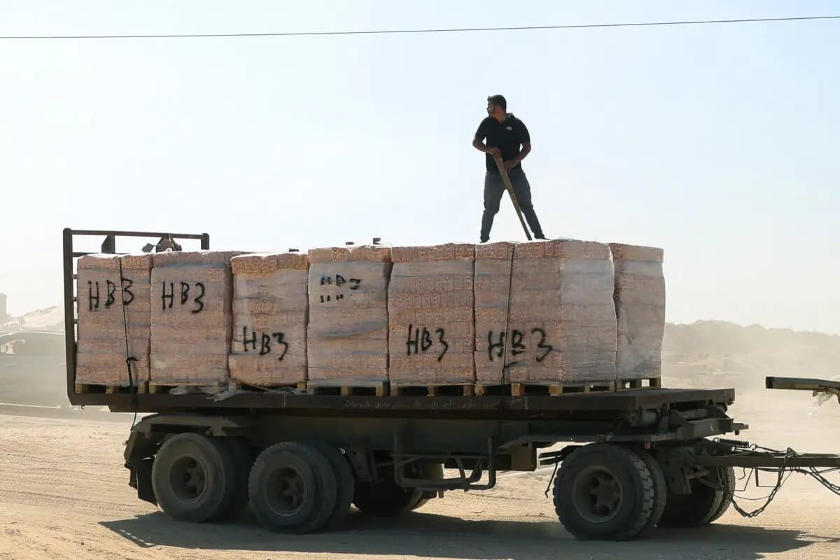 Un hombre palestino en lo alto de un camión de ayuda alimentaria mientras este, junto con otros nueve, ingresaba a la Franja de Gaza a través del cruce de Kissufim, en el sur de Israel, en dirección a Deir al-Balah, el 27 de octubre de 2025. (Bashar Raleb/AFP vía Getty Images).