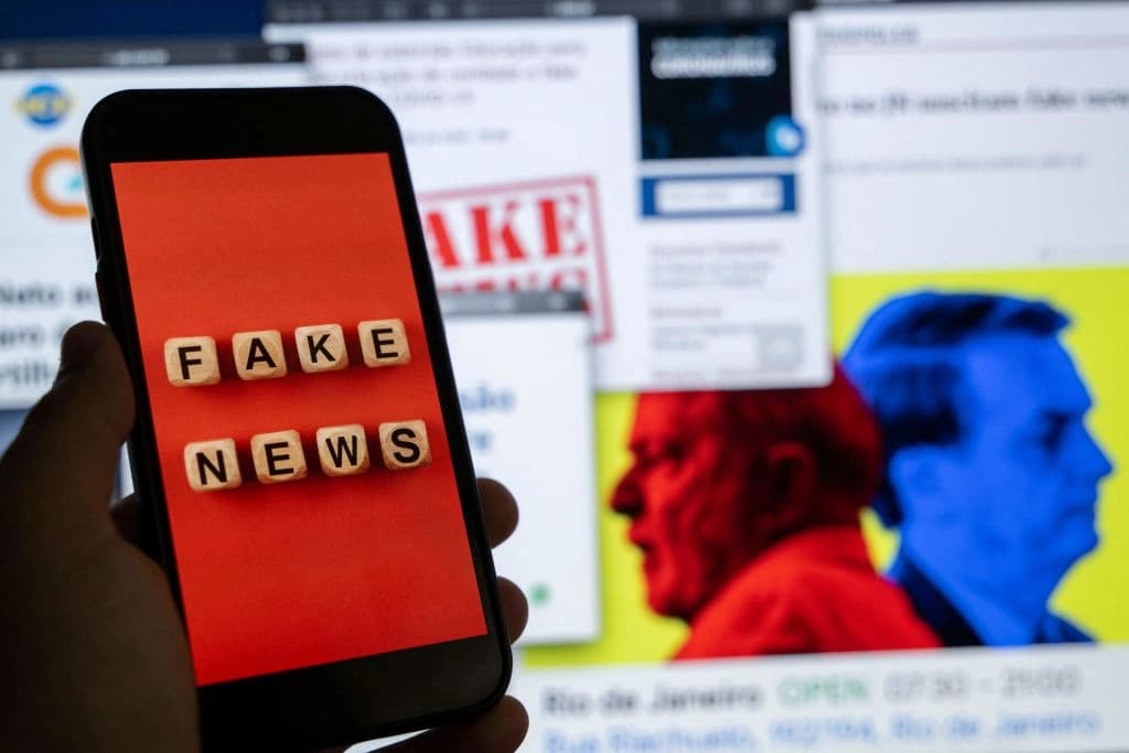 Una ilustración muestra la pantalla de un teléfono inteligente con la frase "Noticias falsas" frente a la pantalla de una computadora de escritorio que muestra varios informes de noticias e investigaciones sobre noticias falsas y desinformación relacionadas con las próximas elecciones presidenciales brasileñas, en Río de Janeiro, Brasil, el 29 de agosto de 2022. (Mauro Pimentel/AFP vía Getty Images).