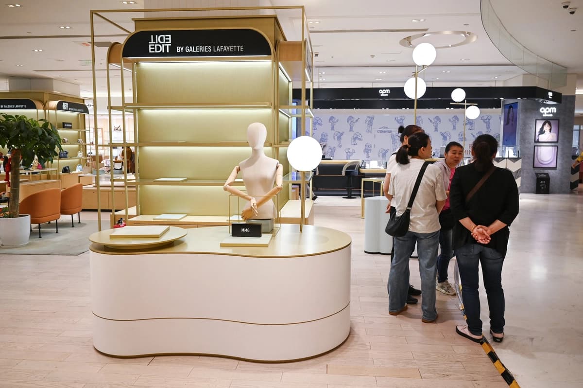 Unos visitantes posan junto a las estanterías vacías del centro comercial francés Galeries Lafayette un día antes de su cierre, en Beijing, el 26 de mayo de 2026. (Greg Baker/AFP vía Getty Images)