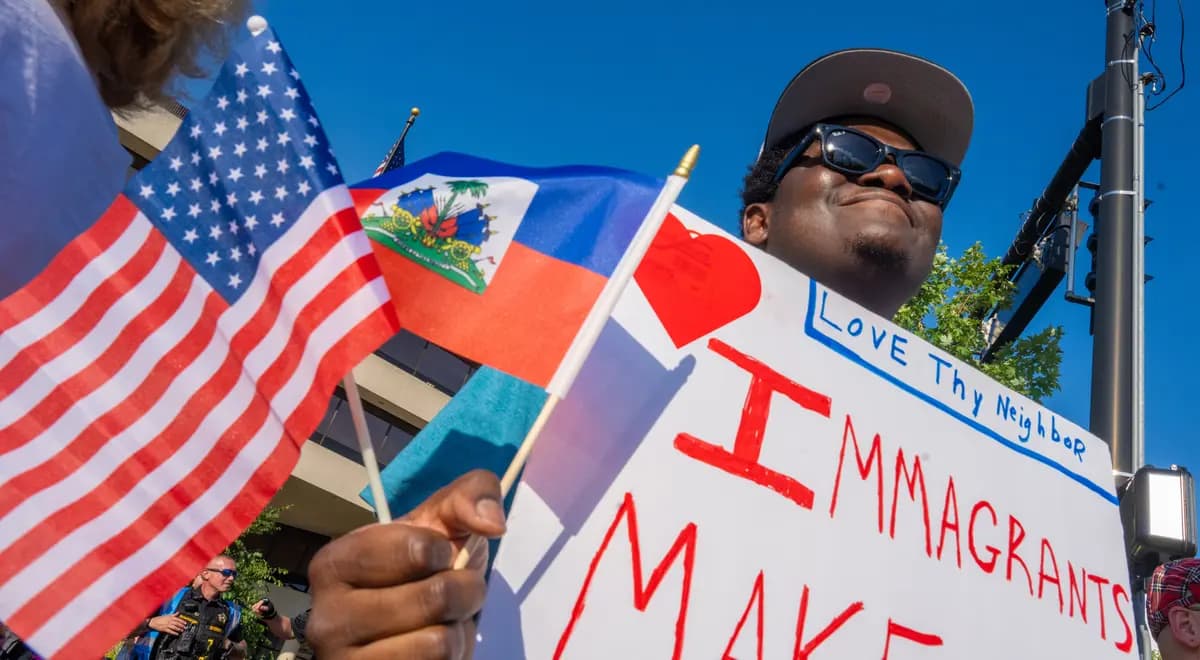 Biassu Pierre, de Haití y beneficiario del estatus de protección, lleva tres años en Springfield, Ohio. Aquí, con banderas haitianas y estadounidenses en la mano, asiste a una manifestación en apoyo a Haití frente al Ayuntamiento de Springfield, en Springfield, Ohio, el 3 de julio de 2026. (Glenn Hartong para The Epoch Times).
