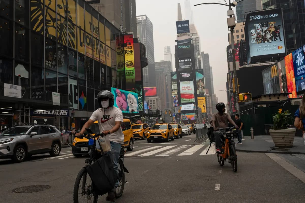 Una persona con cubrebocas anda en bicicleta en Times Square en medio de un cielo lleno de humo en Nueva York el 16 de julio de 2026. (Yuki Iwamura/AP Photo)