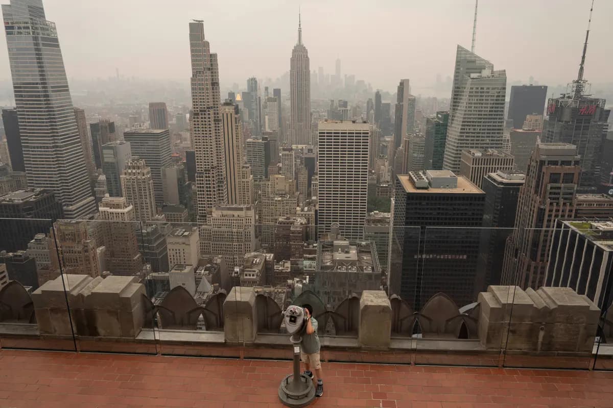 Una persona utiliza binoculares para observar a través del humo desde el mirador Top of The Rock en el Rockefeller Center de Nueva York el 16 de julio de 2026. (Yuki Iwamura/AP Photo)