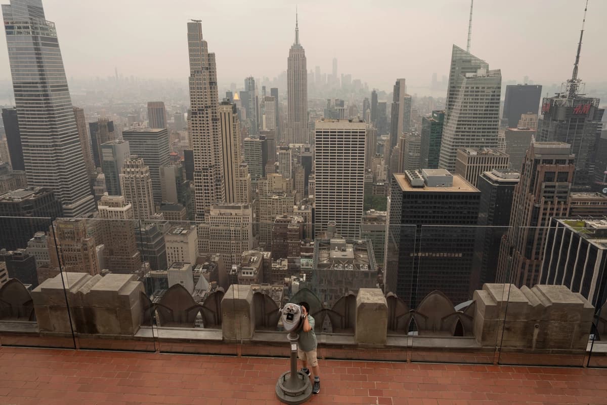 Una persona observa con binoculares cómo el humo de los incendios forestales cubre el cielo desde el mirador Top of the Rock en el Rockefeller Center, el 16 de julio de 2026, en Nueva York. (Foto AP/Yuki Iwamura).