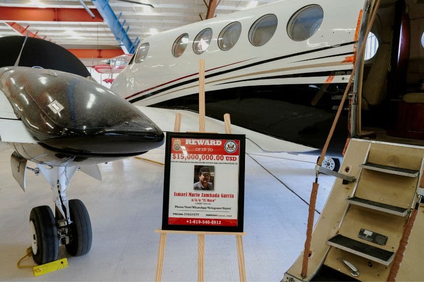 <em>Un cartel de recompensa por el antiguo líder del Cartel de Sinaloa, Ismael "El Mayo" Zambada, junto a un avión Beechcraft King Air, utilizado en julio de 2024 para trasladar a Estados Unidos a Zambada y a Joaquín Guzmán López, hijo del famoso narcotraficante "El Chapo" Guzmán, en el War Eagles Air Museum, donde el avión se encuentra cedido por el FBI, en Santa Teresa, Nuevo México, EE. UU., el 9 de julio de 2026. (REUTERS/Paul Ratje/Foto de archivo)</em>