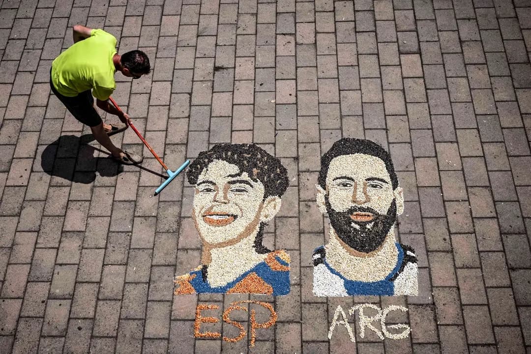 El artista kosovar Alkent Pozhegu da los últimos toques a un mosaico en el suelo, realizado con granos y semillas, que representa al delantero argentino n.º 10, Lionel Messi (derecha), y al delantero español n.º 19, Lamine Yamal, en la ciudad de Gjakova, Kosovo, el 16 de julio de 2026. (Armend Nimani/AFP vía Getty Images)