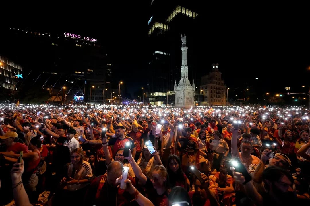 Los aficionados españoles encienden las linternas de sus teléfonos mientras ven la final de la Copa Mundial de 2026 entre España y Argentina, que se transmite en pantallas gigantes situadas bajo la estatua de Cristóbal Colón en la Plaza de Colón, en Madrid, España, el 19 de julio de 2026. (Paul Hanna/AFP vía Getty Images)