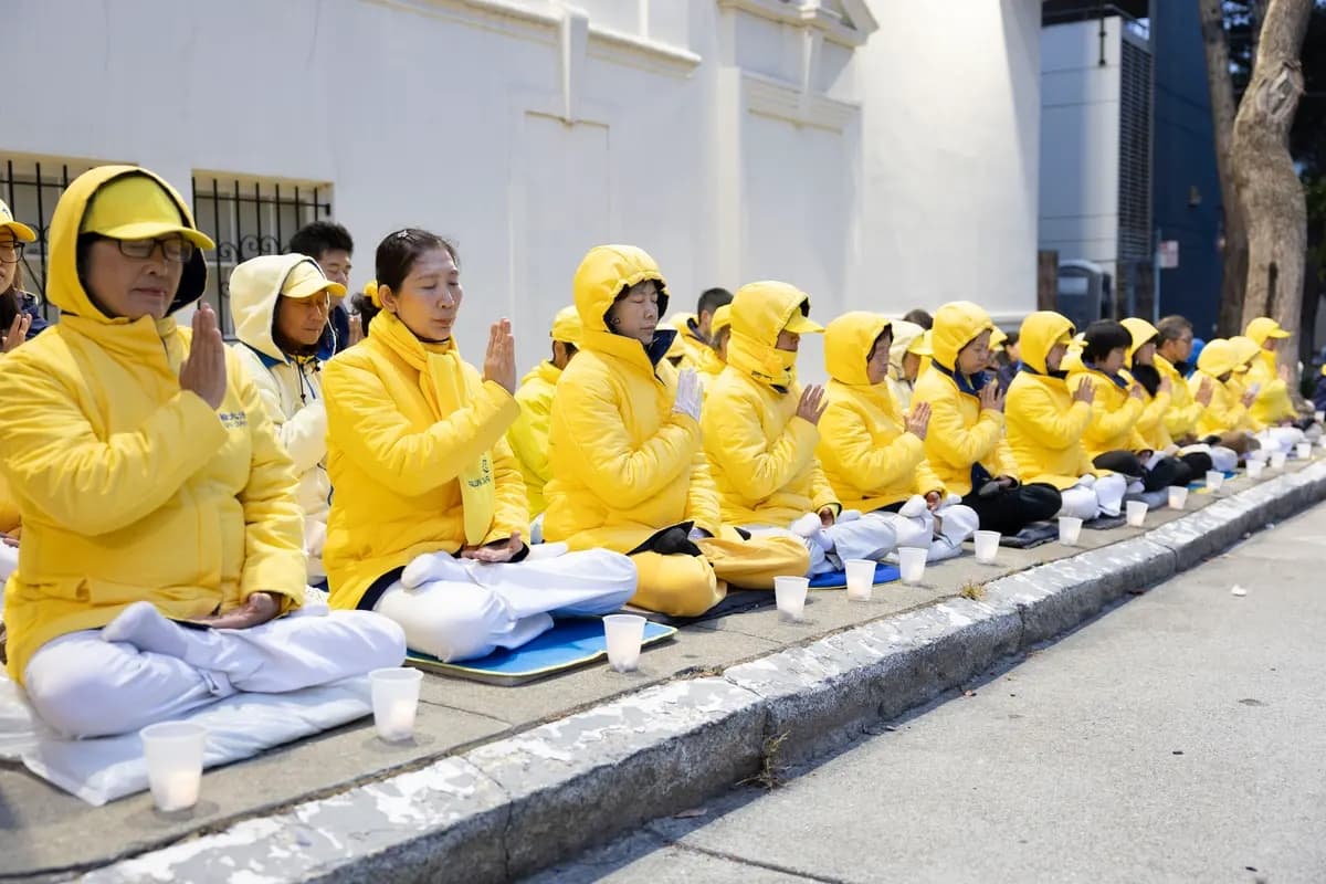 La luz procedente de la parte superior del edificio del Consulado General de China en San Francisco iluminó a los practicantes de Falun Gong que protestaban el 19 de julio de 2026. (Lear Zhou/Epoch Times)