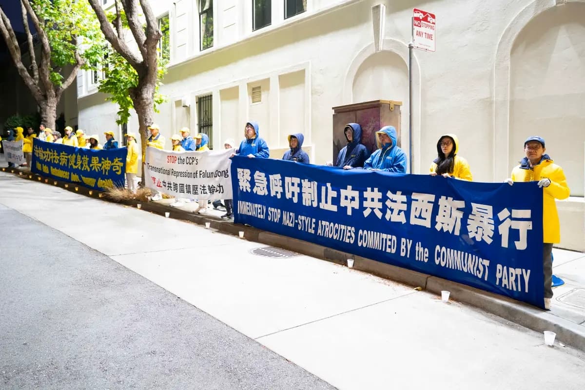 La luz procedente de la parte superior del edificio del Consulado General de China en San Francisco iluminó a los practicantes de Falun Gong que protestaban el 19 de julio de 2026. (Lear Zhou/Epoch Times)