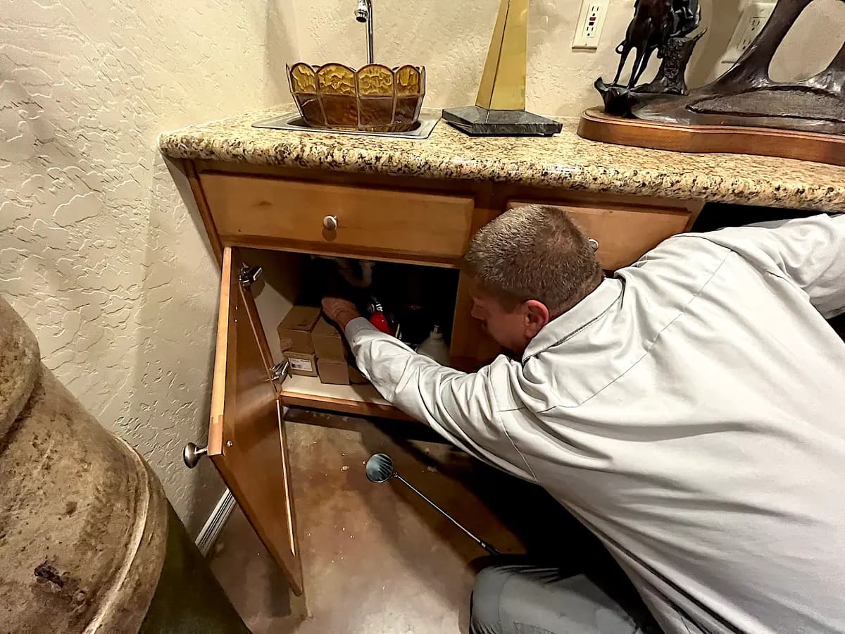 Mike Golleher, especialista en escorpiones, revisa si hay escorpiones debajo del fregadero de la cocina en Tempe, Arizona, el 24 de junio de 2026. (Allan Stein/The Epoch Times)