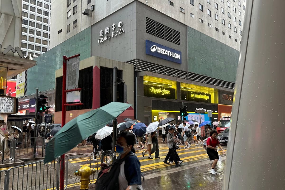 Los transeúntes caminan por el distrito de Mong Kok, en Hong Kong, bajo fuertes lluvias y vientos antes de la llegada del tifón Noul, el 25 de julio de 2026. (Chan Ho-him/AP Photo)