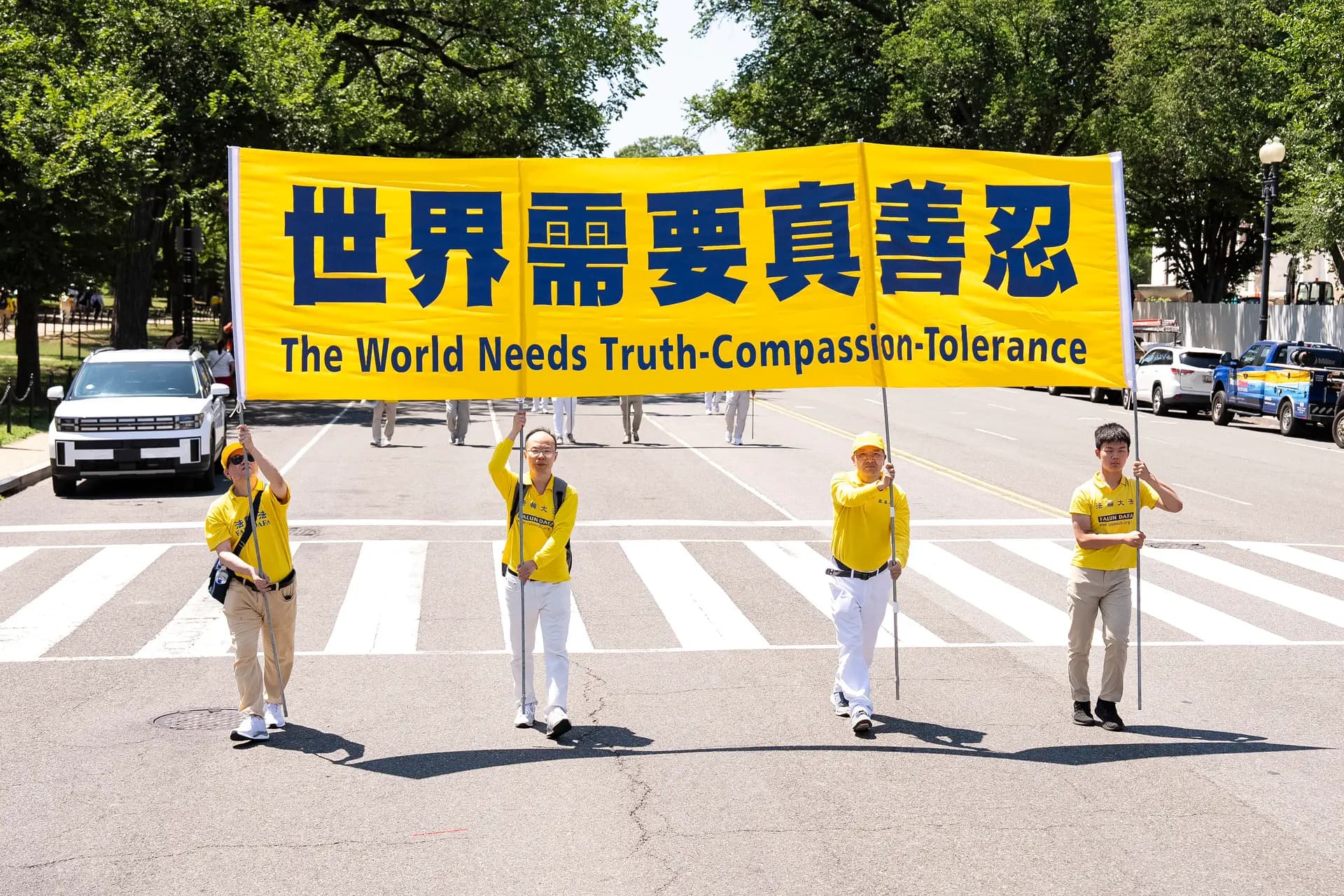 Practicantes de Falun Dafa sostienen una pancarta que dice "El mundo necesita Verdad-Benevolencia-Tolerancia" en Washington el 23 de julio de 2026. (Larry Dye/The Epoch Times)