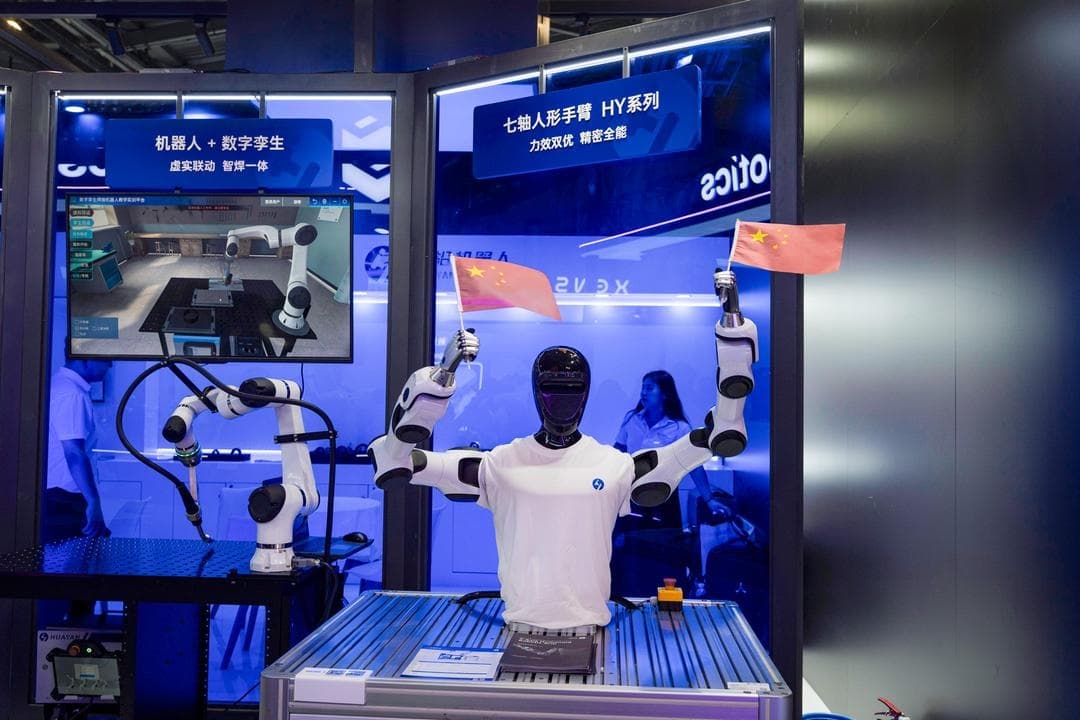 Un robot humanoide de la empresa china Huayan Robotics agita banderas nacionales chinas durante la Conferencia Mundial de IA en Shanghái el 18 de julio de 2026. (Ng Han Guan/AP Photo)