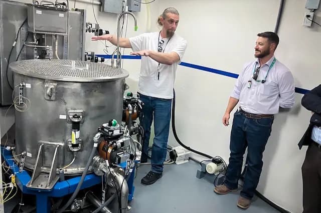 El director de operaciones de Deployable Energy, Lance Maul, explica cómo el reactor Unity de la empresa —transportado desde Texas hasta Idaho en la caja de una camioneta Ford F-150— utiliza 696 barras de uranio en un contenedor con forma de tina de 63 galones para generar electricidad, en el Laboratorio Nacional de Idaho, al oeste de Idaho Falls, Idaho, en junio de 2026. (John Haughey/The Epoch Times).