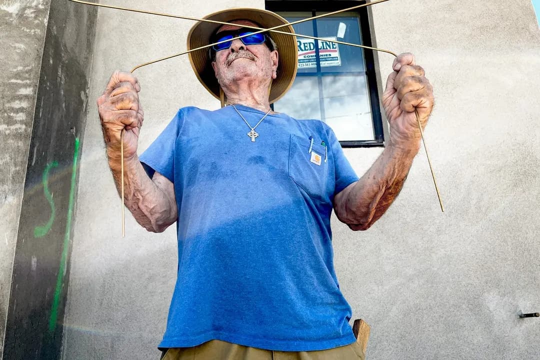 El zahorí de agua profesional Jack Coel muestra cómo utiliza un par de varillas de latón para localizar agua en un sitio de construcción en Phoenix el 13 de julio de 2026. (Allan Stein/The Epoch Times)
