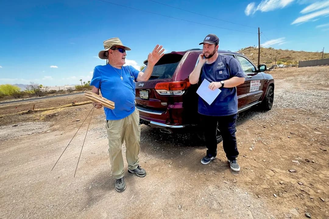 El zahorí de agua profesional Jack Coel (izquierda) se reúne con el gerente de construcción de Diamante Homes, Tanner Cook, para discutir la estrategia de búsqueda de agua utilizando varillas de latón, en Phoenix, el 13 de julio de 2026. (Allan Stein/The Epoch Times)