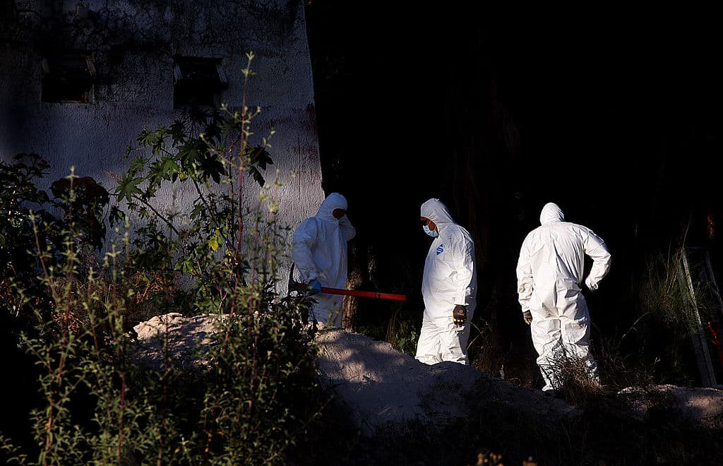 Personal forense trabaja en una fosa clandestina hallada en el jardín de la sede de la Federación de Estudiantes de Guadalajara, en Guadalajara, México, el 15 de diciembre de 2011. Los cuerpos de cinco personas fueron exhumados después de que las autoridades iniciaran una investigación por la desaparición, cinco días antes, de cuatro estudiantes y del padre de uno de ellos. (Héctor Guerrero/AFP vía Getty Images)