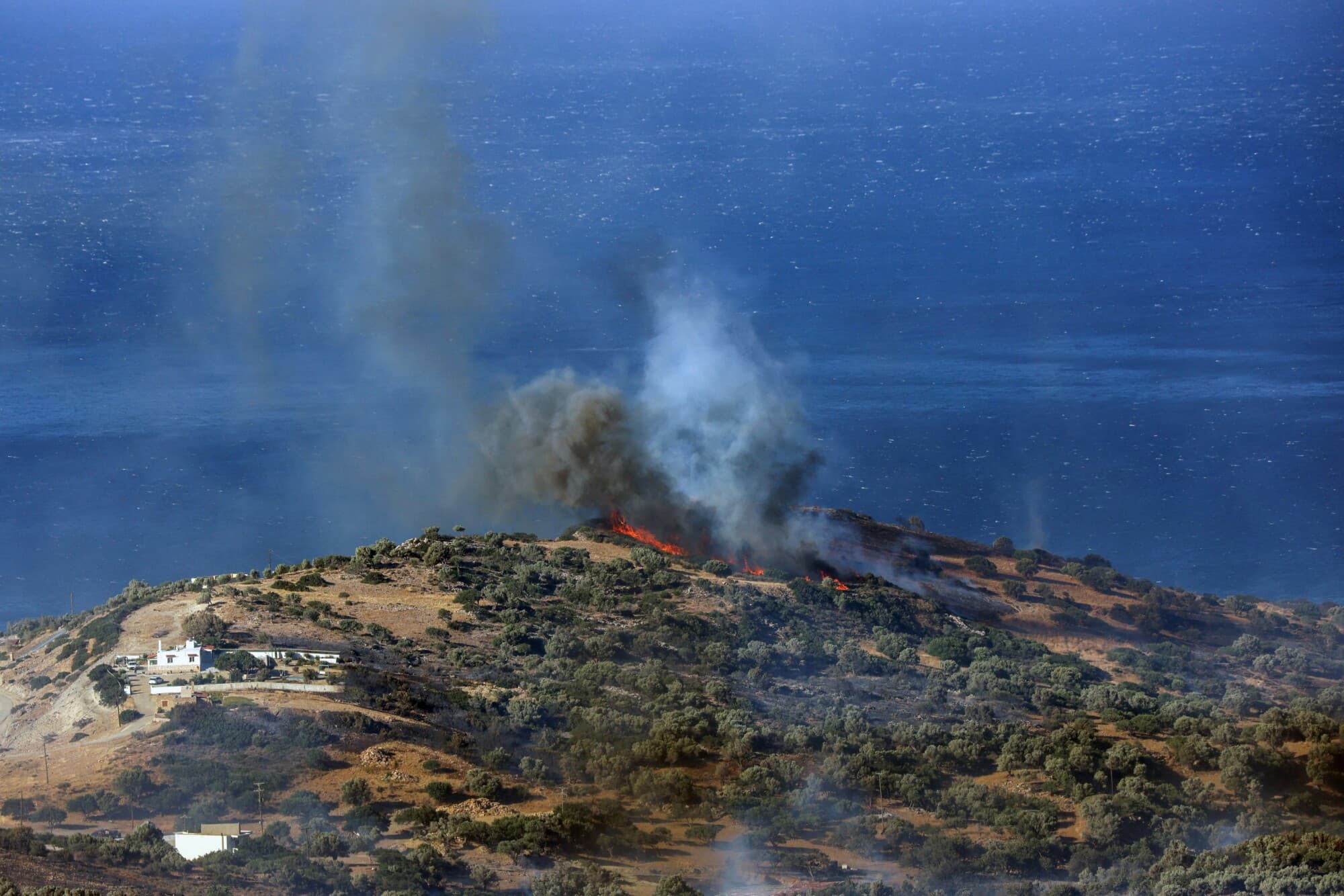 Llamas y humo se elevan mientras un incendio forestal arde cerca de la playa de Triopetra en la isla de Creta, Grecia, 30 de julio de 2026. (Stefanos Rapanis/Reuters).