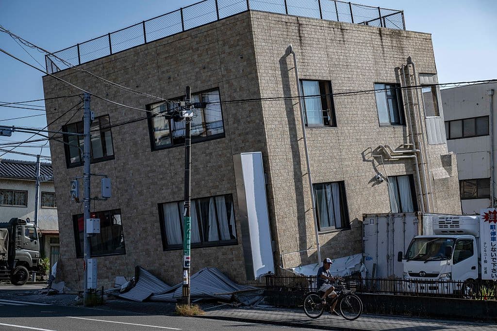 Un hombre pasa en bicicleta junto a un edificio dañado en Yatsushiro, en la prefectura de Kumamoto, el 30 de julio de 2026, tras el terremoto del 28 de julio. (Yuichi YAMAZAKI / AFP vía Getty Images)