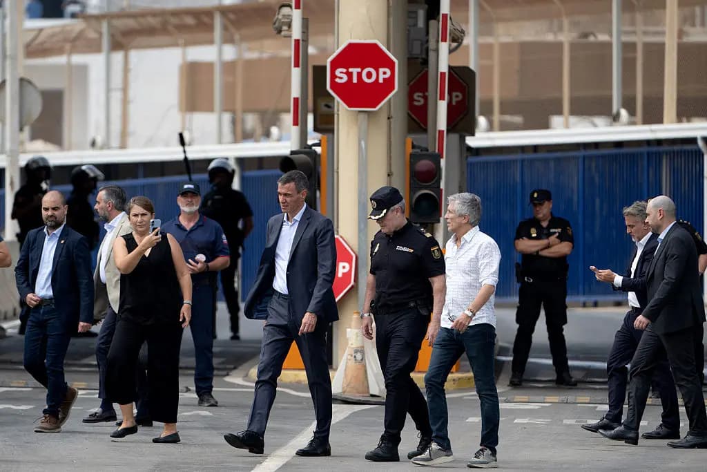 El presidente del gobierno español, Pedro Sánchez (C), y el ministro del Interior, Fernando Grande Marlaska, caminan junto a la valla fronteriza de Tarajal, entre el enclave español de Ceuta, en el norte de África, y Marruecos, durante una visita para gestionar una de las mayores crisis de inmigración ilegal en la frontera del país, mientras miles de migrantes cruzaban durante la noche desde Marruecos el 31 de julio de 2026. (Jorge Guerrero/AFP vía Getty Images)