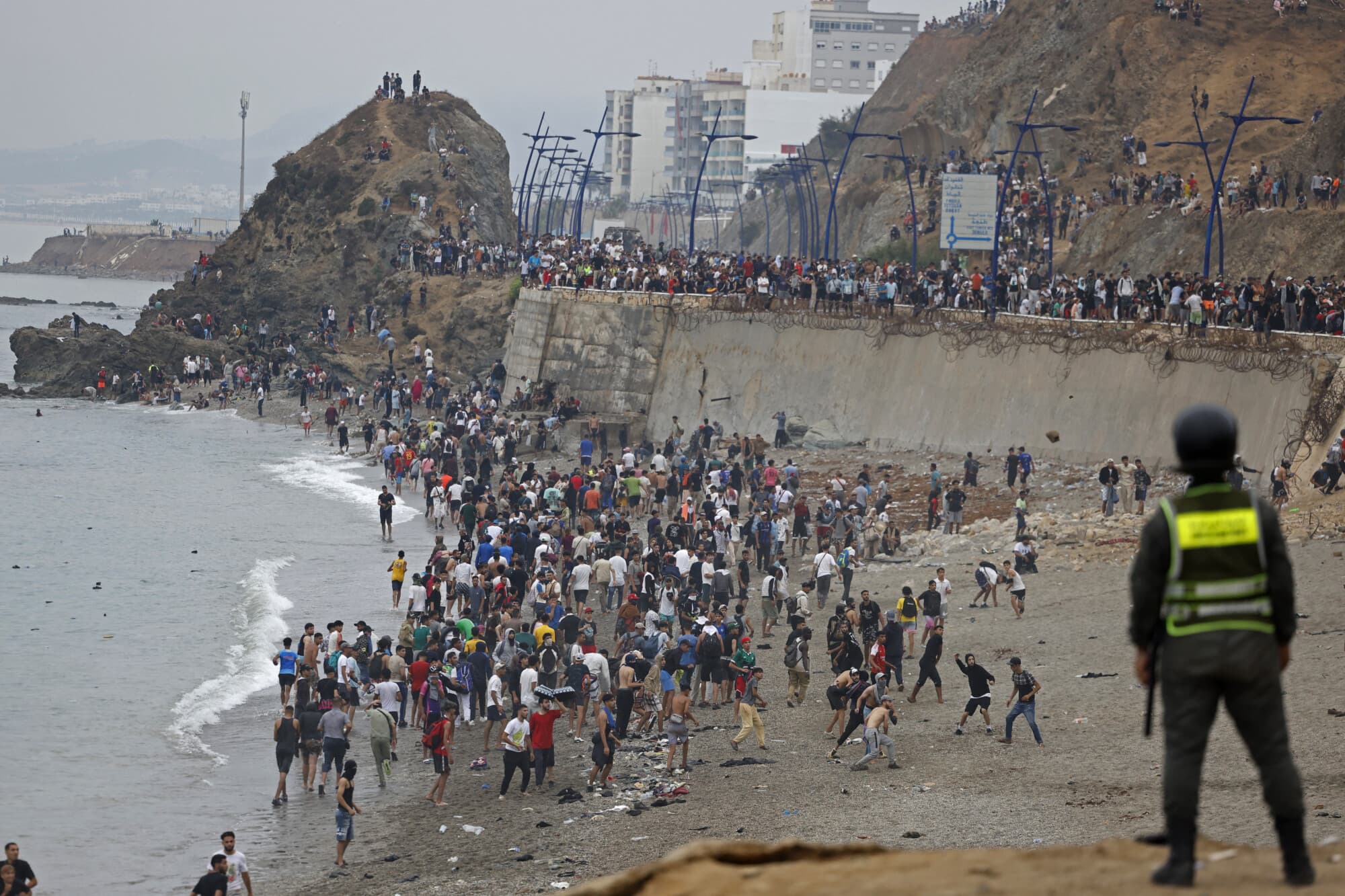 Migrantes se concentran junto a la valla en el lugar de los enfrentamientos cerca de Fnideq, en la frontera entre Marruecos y España, el 31 de julio de 2026. (Abdel Majid BZIOUAT / AFP vía Getty Images)