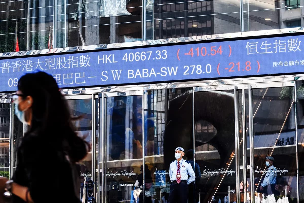 Tras la decisión de última hora de suspender la OPI sin precedentes del gigante de tecnología financiera Ant Group la noche anterior, la actividad bursátil de Alibaba Group Holding Ltd (BABA-SW) (parte superior C) se muestra sobre un guardia de seguridad mientras este se encuentra frente a las torres de Exchange Square en Hong Kong el 4 de noviembre de 2020. (Anthony Wallace/AFP vía Getty Images)