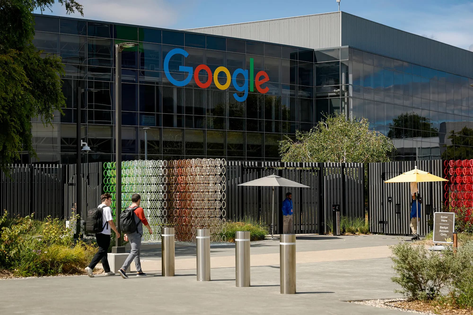 <em>Varias personas pasan junto a un edificio en el campus de la sede central de Google en Mountain View, California, el 23 de julio de 2025. Grandes nombres del sector tecnológico como Google, Meta y Amazon Web Services han lanzado sus propios programas de capacitación para trabajadores cualificados con el objetivo de ampliar su plantilla. (Justin Sullivan/Getty Images)</em>