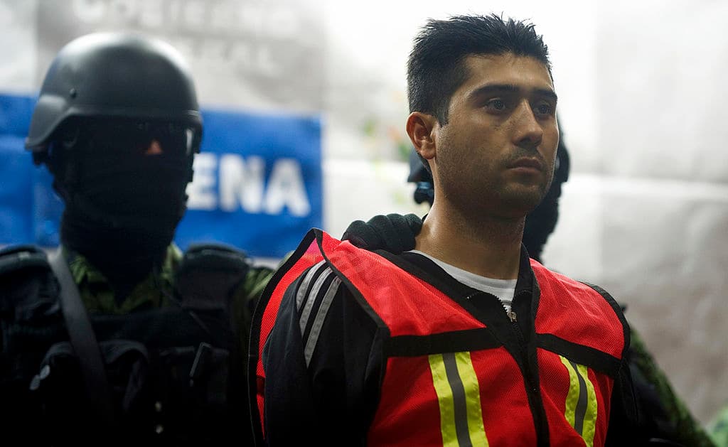 <em>Soldados del Ejército de México escoltan a Erick Valencia Salazar, alias El 85, como presunto líder del Cártel Jalisco Nueva Generación, durante su presentación ante la prensa el 12 de marzo de 2012 en la Ciudad de México. Valencia fue detenido el 9 de marzo durante un operativo militar en Guadalajara. (Yuri Cortez/AFP vía Getty Images)</em>