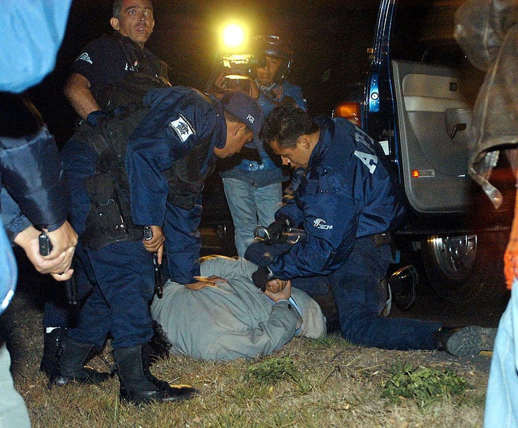 <em>Policías de la Agencia Federal de Investigación (AFI) realizan un arresto cerca del penal de La Palma antes del traslado de Iván Archivaldo Guzmán, el Chapito, en el Estado de México, el 9 de junio de 2005. Jueces y responsables de la lucha antidrogas en México mantenían una disputa sobre la responsabilidad de varias decisiones polémicas, entre ellas la confusa situación jurídica del hijo de Joaquín "el Chapo" Guzmán. (Hernán Vázquez / Agencia MVT / AFP vía Getty Images)</em>