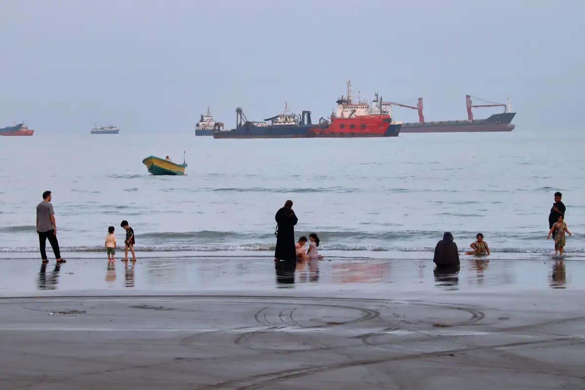 <em>La gente pasa tiempo en una playa mientras barcos comerciales anclan en el Estrecho de Ormuz frente a Bandar Abbas, Irán, el 5 de agosto de 2026. (Amirhosein Khorgooi/ISNA vía AP).</em>