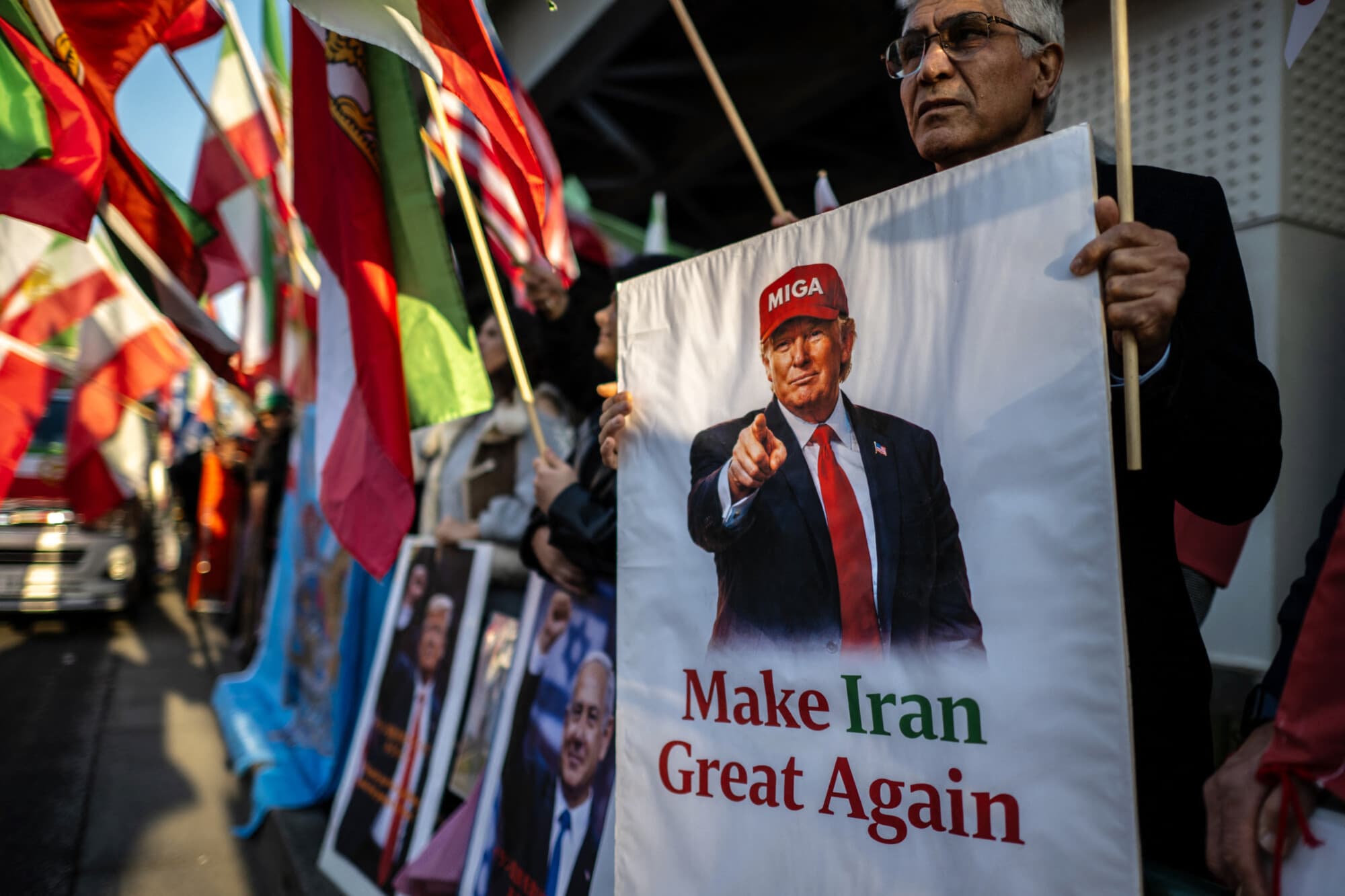Un manifestante sostiene un cartel del presidente de EE. UU., Donald Trump, con el texto "Make Iran Great Again" (Hagamos grande a Irán de nuevo), mientras otros ondean banderas iraníes anteriores a la Revolución Islámica de 1979 durante una manifestación en apoyo al cambio político cerca de la embajada de Irán en Tokio, el 17 de marzo de 2026. (Philip FONG / AFP vía Getty Images)