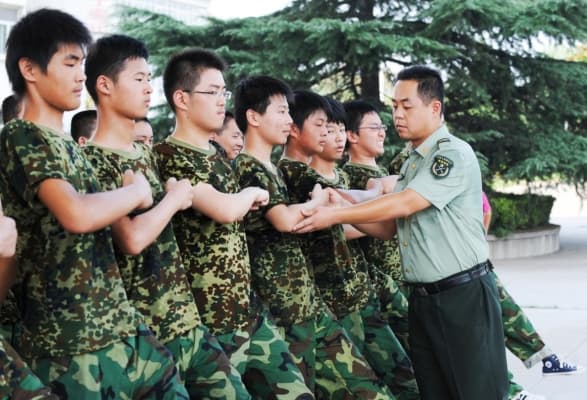Estudiantes chinos practican la marcha bajo la supervisión de un soldado del Ejército Popular de Liberación (EPL) durante su semana de servicio militar de primer año de preparatoria en una base militar en Hefei, provincia de Anhui, al este de China, el 5 de agosto de 2010. (STR/AFP/Getty Images)