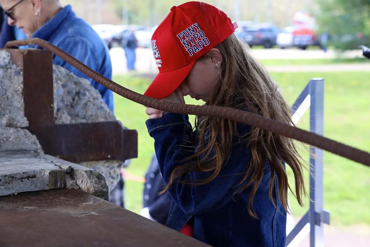 Una niña reza junto a la viga en I que se exhibe durante la gira “Steel Across America”. (Tunnel to Towers)