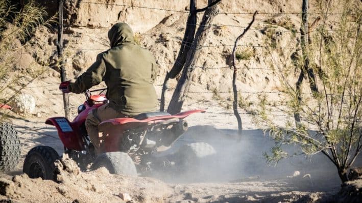 Los traficantes de personas conducen vehículos todo terreno en el lado mexicano del muro fronterizo de Estados Unidos cerca de Jacumba, California, el 31 de octubre de 2023. (John Fredricks/The Epoch Times)