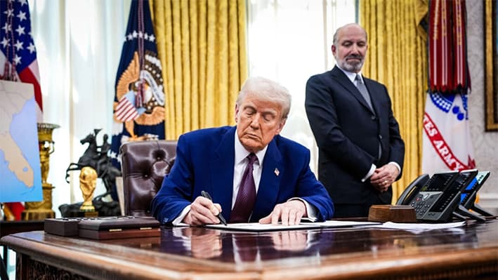 El presidente Donald Trump, acompañado por el candidato a secretario de Comercio Howard Lutnick, firma una orden ejecutiva sobre aranceles recíprocos en el Despacho Oval el 13 de febrero de 2025. (Andrew Harnik/Getty Images)