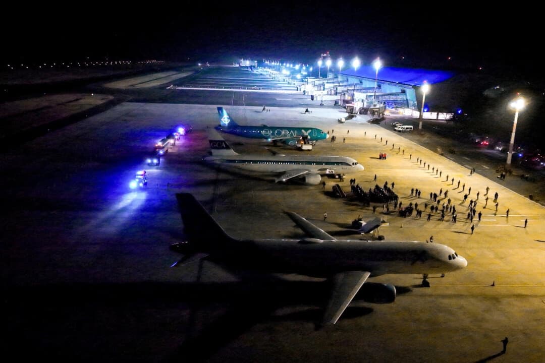 Agentes de la policía salvadoreña escoltan a presuntos miembros de la banda venezolana Tren de Aragua, recientemente deportados por el gobierno de EE. UU. para ser encarcelados en la prisión del Centro de Confinamiento de Terrorismo (CECOT), como parte de un acuerdo con el gobierno salvadoreño, en el Aeropuerto Internacional de El Salvador en San Luis Talpa, El Salvador, el 16 de marzo de 2025. (Secretaria de Prensa de la Presidencia/Folleto vía Reuters)