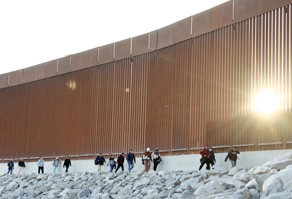 Inmigrantes ilegales caminan a lo largo de la valla fronteriza en su camino para ser procesados por agentes de la Patrulla Fronteriza de EE. UU. después de cruzar a Arizona desde México, en Yuma, Arizona, el 11 de mayo de 2023. (Mario Tama/Getty Images)