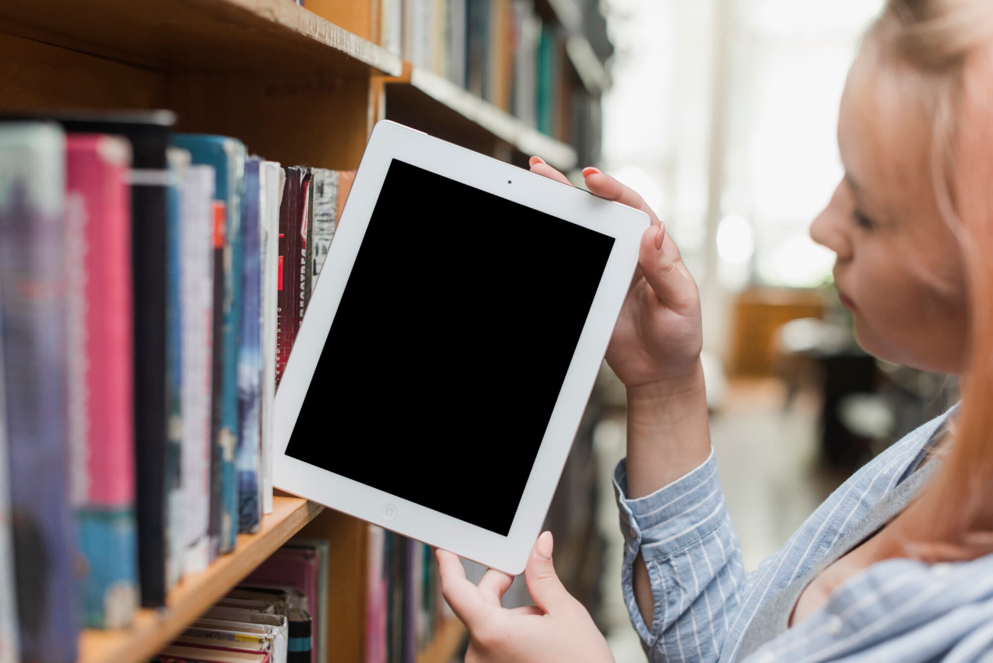 Adolescente toma una tablet de la biblioteca (Imagen de freepik)