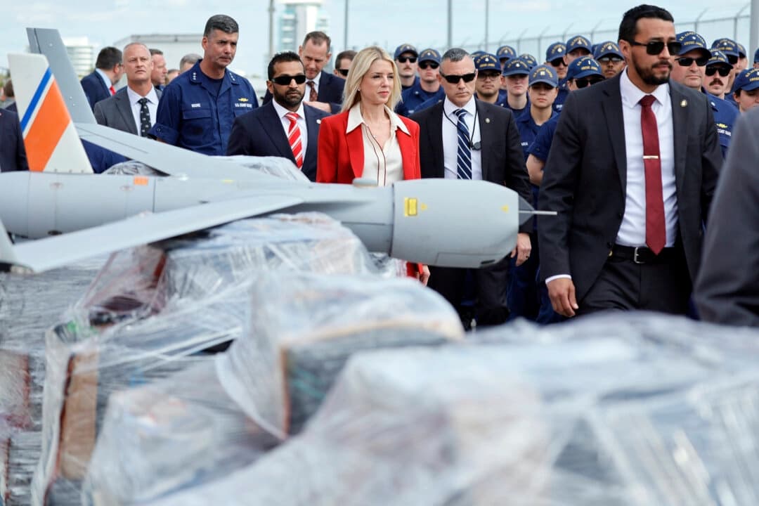 La fiscal general Pam Bondi y el director del FBI Kash Patel pasan junto a palés de narcóticos envueltos en plástico y un dron utilizado en las investigaciones cuando llegan a una conferencia de prensa en Port Everglades, Florida, el 9 de abril de 2025. (Amy Beth Bennett/South Florida Sun-Sentinel vía AP).