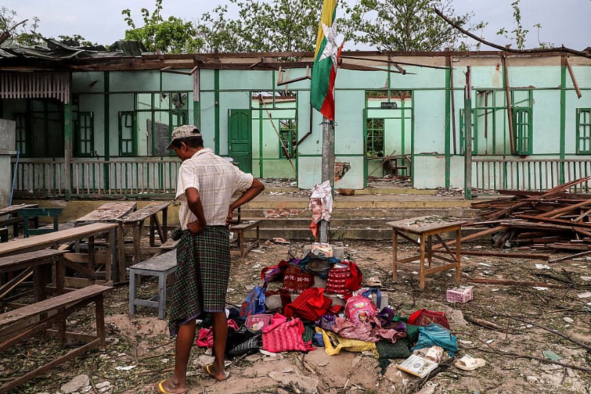 Un hombre se encuentra frente a un edificio escolar dañado en un bombardeo llevado a cabo por el ejército de Myanmar en la aldea Ohe Htein Twin, en el municipio de Tabayin, región de Sagaing, el 12 de mayo de 2025. (AFP vía Getty Images)