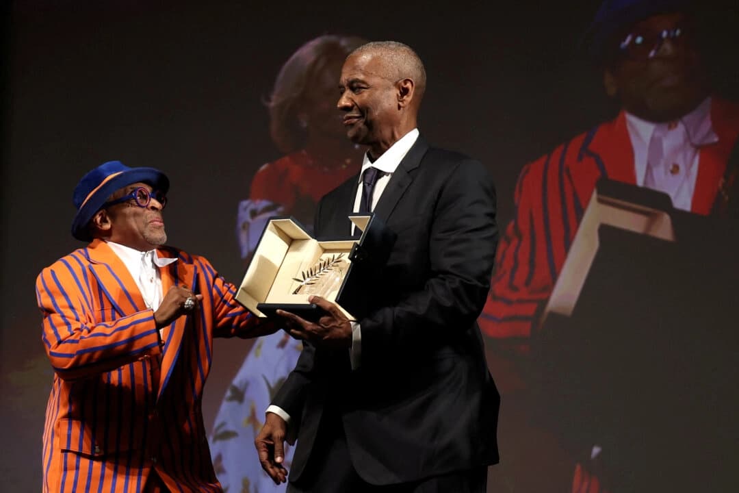 El actor Denzel Washington recibe la Palma de Oro Honoraria de manos del director y productor ejecutivo Spike Lee antes de la proyección de la película "Highest 2 Lowest" en la 78.ª edición del Festival de Cine de Cannes, en Cannes, sur de Francia, el 19 de mayo de 2025. (Valery Hache/Pool vía Reuters).