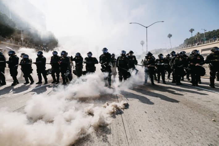 Agentes del orden con equipo antidisturbios avanzan durante las protestas en Los Ángeles, el 8 de junio de 2025. (David Pashaee/Middle East Images/AFP vía Getty Images)