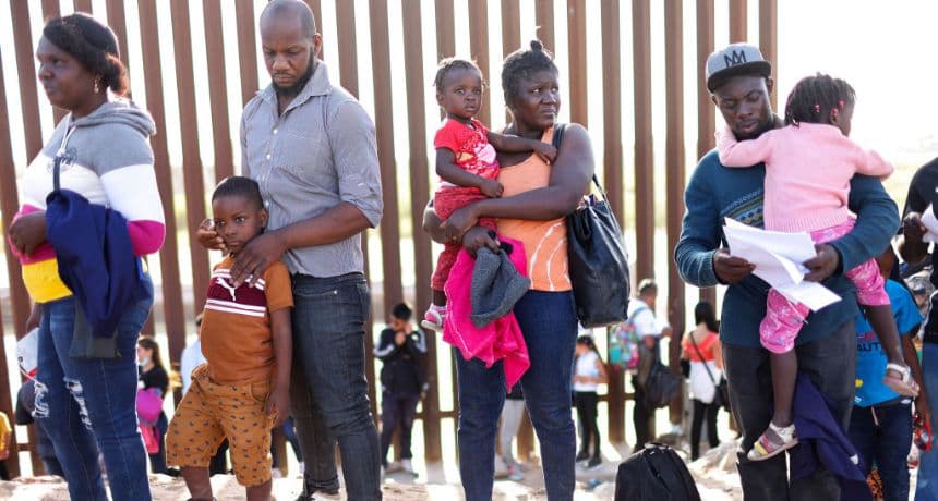 Inmigrantes procedentes de Haití, que cruzaron por un hueco en la valla fronteriza entre Estados Unidos y México, esperan en fila para ser procesados por la Patrulla Fronteriza de Estados Unidos, el 20 de mayo de 2022 en Yuma, Arizona. (Mario Tama/Getty Images)