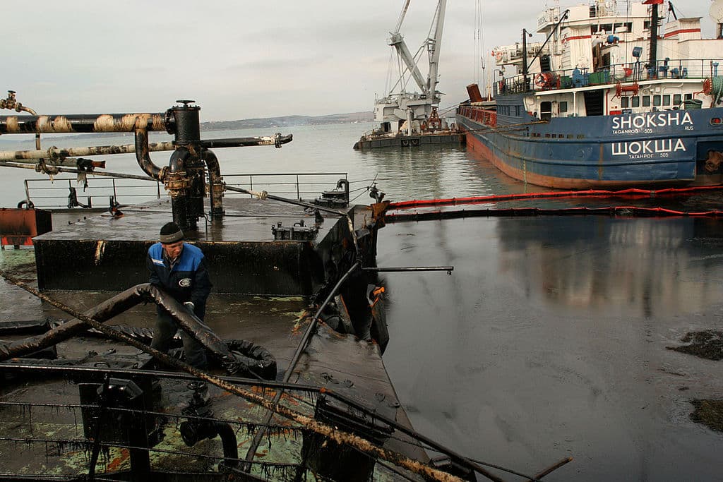 PORT KAVKAZ, RUSIA: Un trabajador intenta evitar que el petróleo se derrame por la popa del buque Voga-Neft, un petrolero que sufrió una grieta en el casco, el 17 de noviembre de 2007 en Port Kavkaz, en el estrecho de Kerch, en el mar Negro, en la región de Krasnodar, Rusia. Una fuerte tormenta hundió tres barcos rusos que transportaban azufre, agrietó el casco de un petrolero ruso y partió en dos otro petrolero ruso frente al puerto ucraniano de Kerch el 11 de noviembre, derramando hasta 2000 toneladas de fuelóleo en lo que un funcionario ruso calificó de «desastre medioambiental». (Foto de Oleg Klimov/Epsilon/Getty Images)